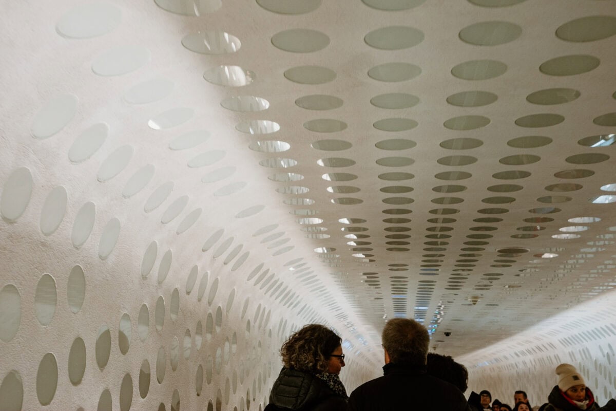 Besucher in modernem Tunnel mit ovalen Mustern an Wänden