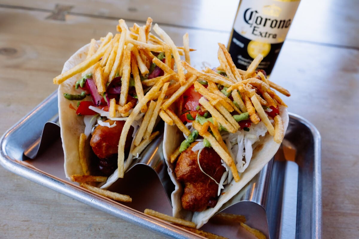 Zwei Tacos mit Pommes und Gemüse neben Corona-Bier