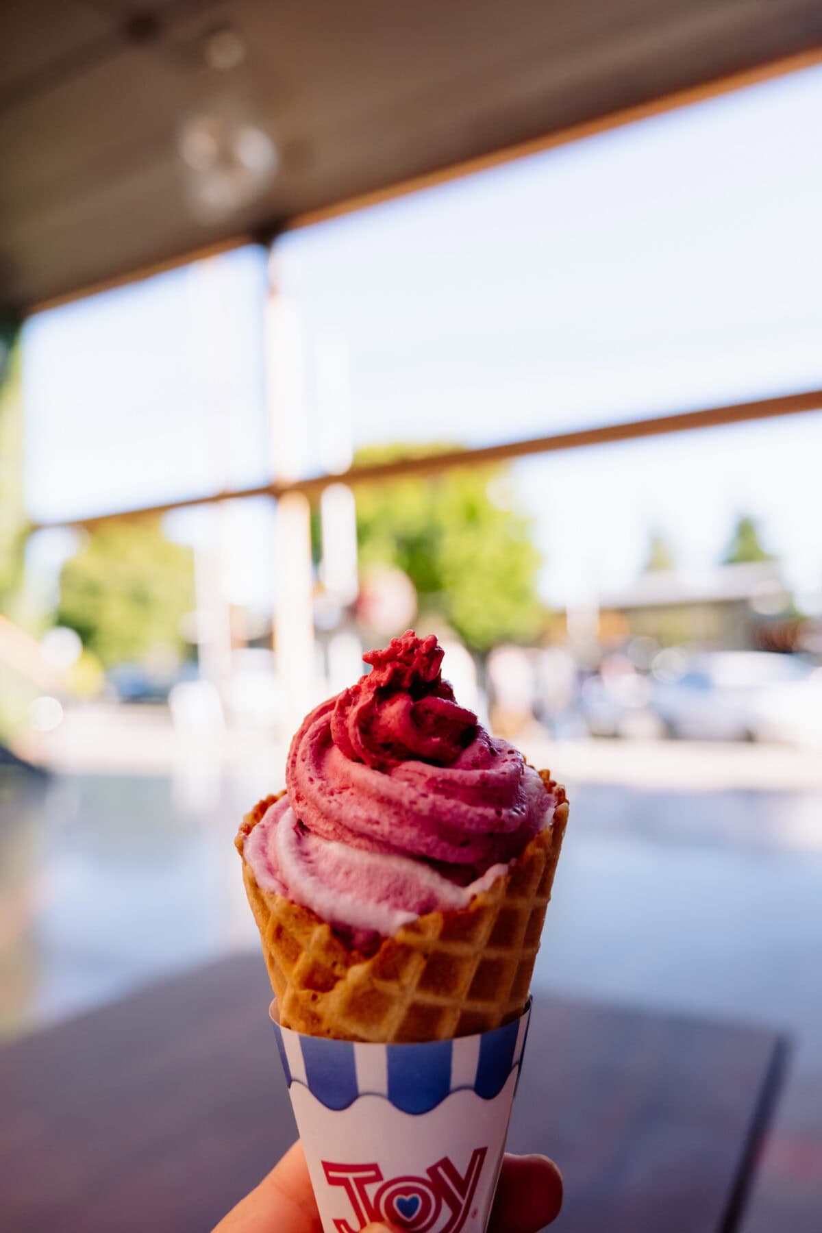 Himbeer-Softeis in Waffelbecher an sonnigem Tag