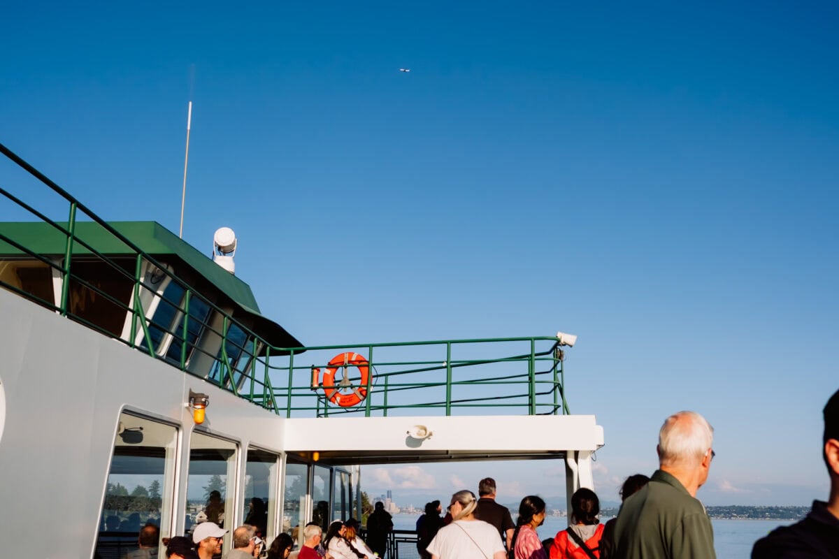Passagiere auf dem Deck einer Fähre bei blauem Himmel