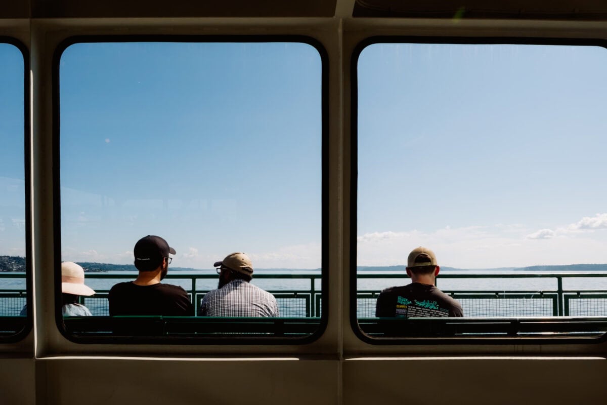 Drei Passagiere blicken durch Fährfenster auf das Meer