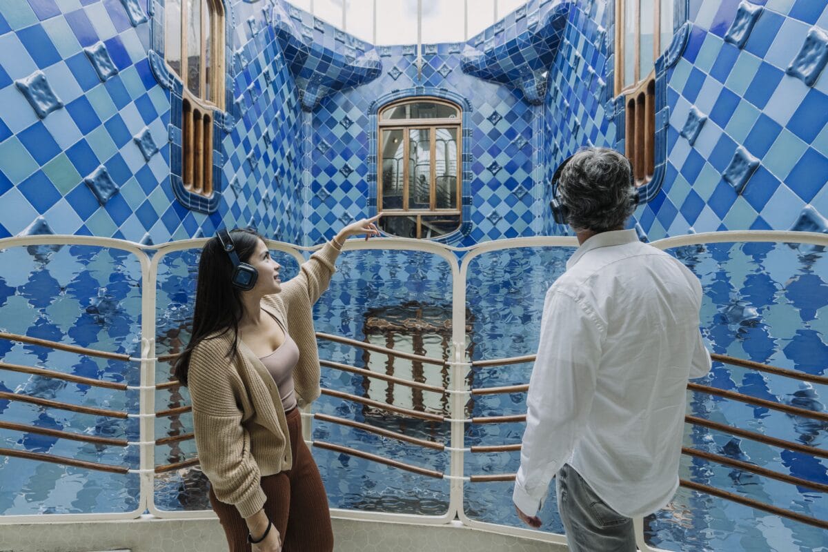 Paar mit Kopfhörern bewundert blaue Kacheln im Pati Blau der Casa Batlló