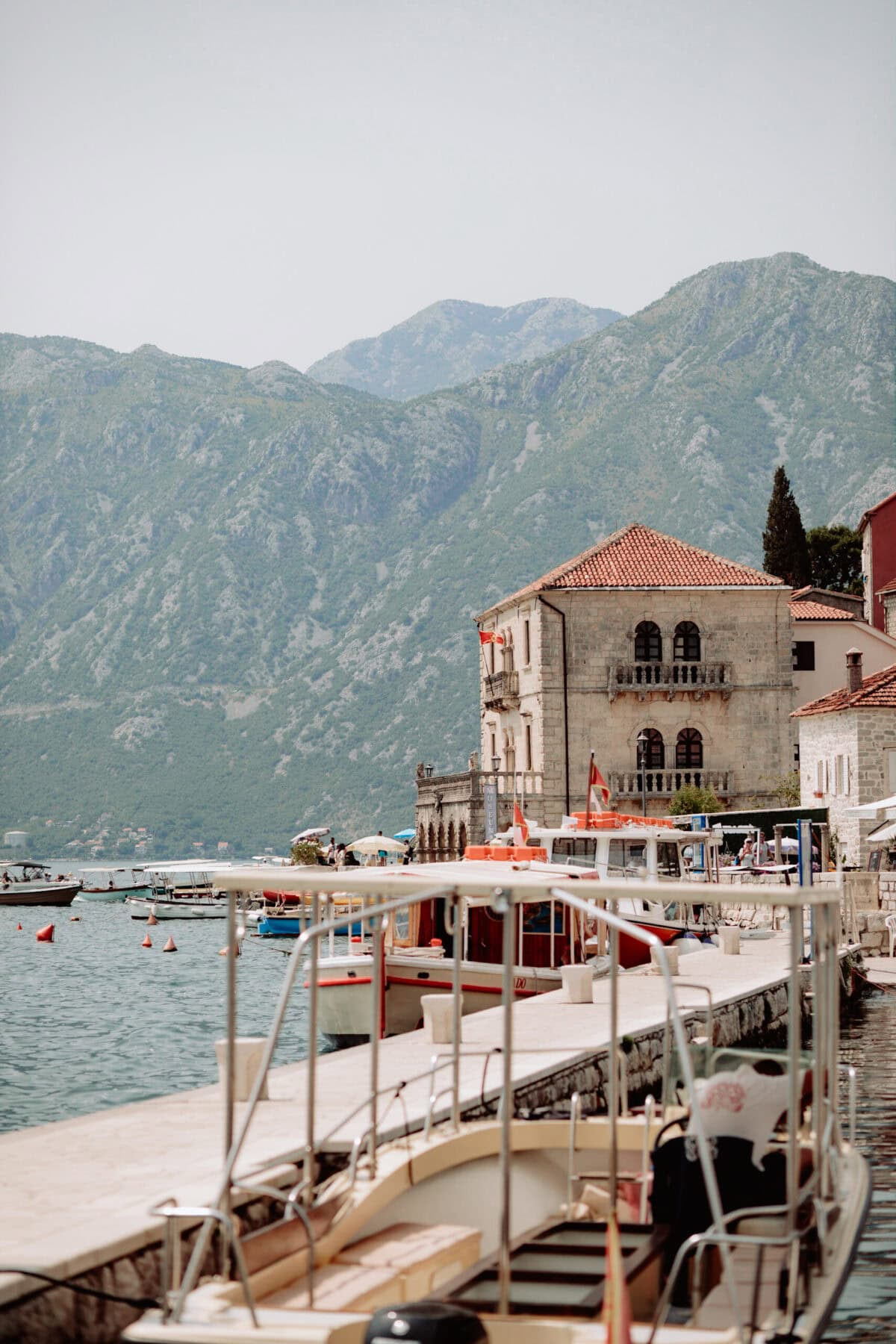 Historisches Gebäude am Hafen von Perast mit Bergen im Hintergrund