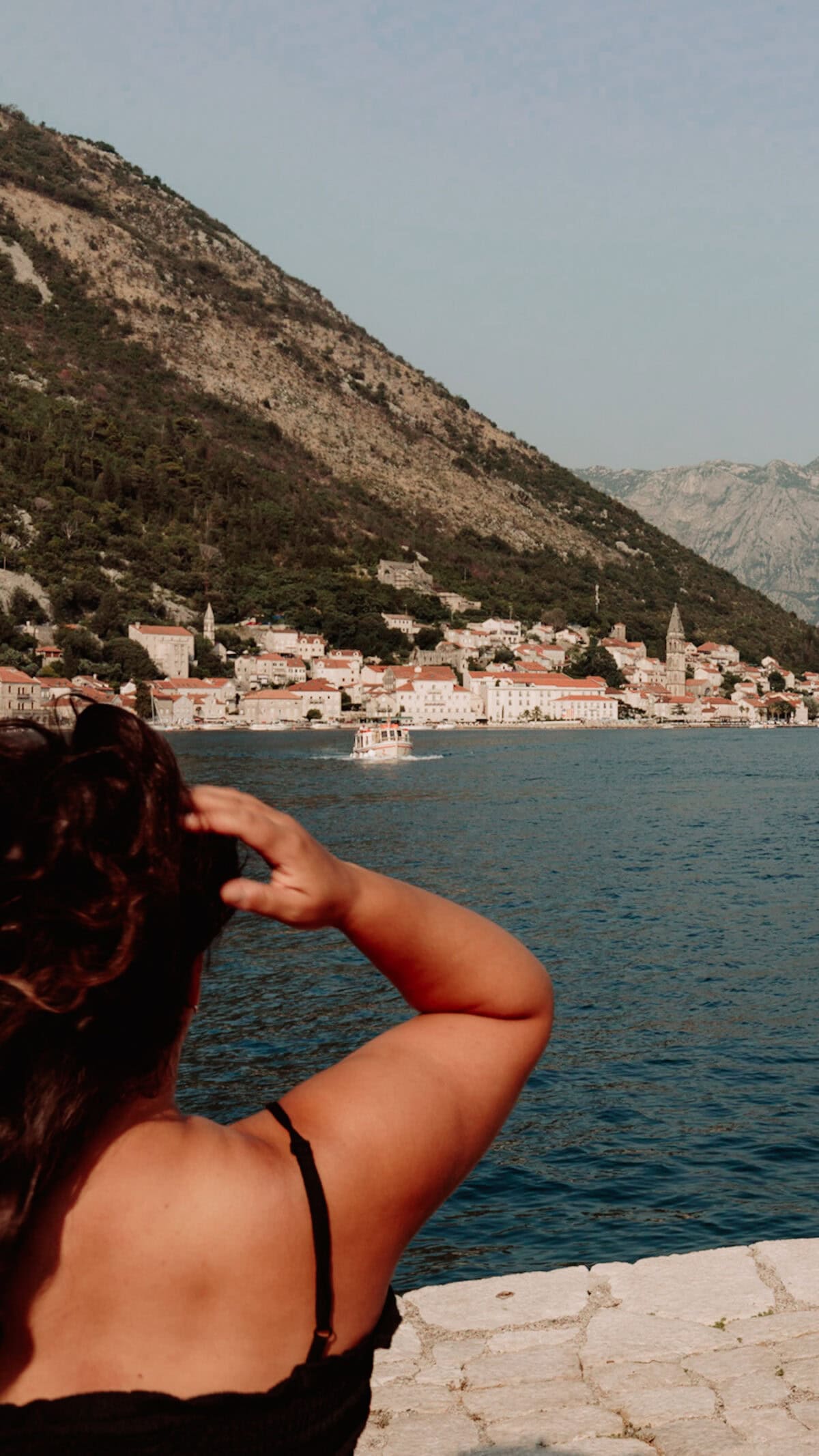 Frau blickt auf Küstenstadt Perast in Montenegro