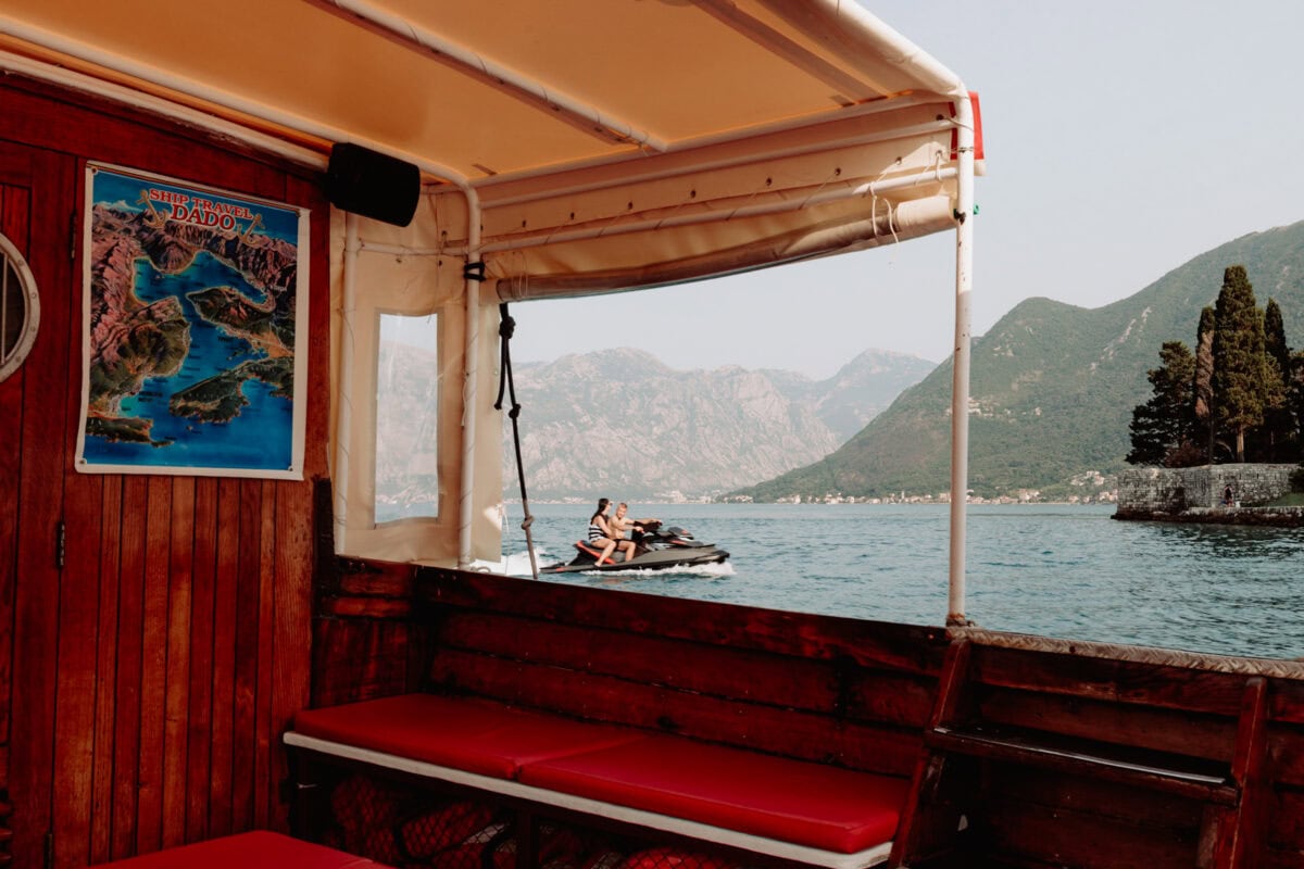 Touristenboot in der Bucht von Kotor mit Jetski und Bergen